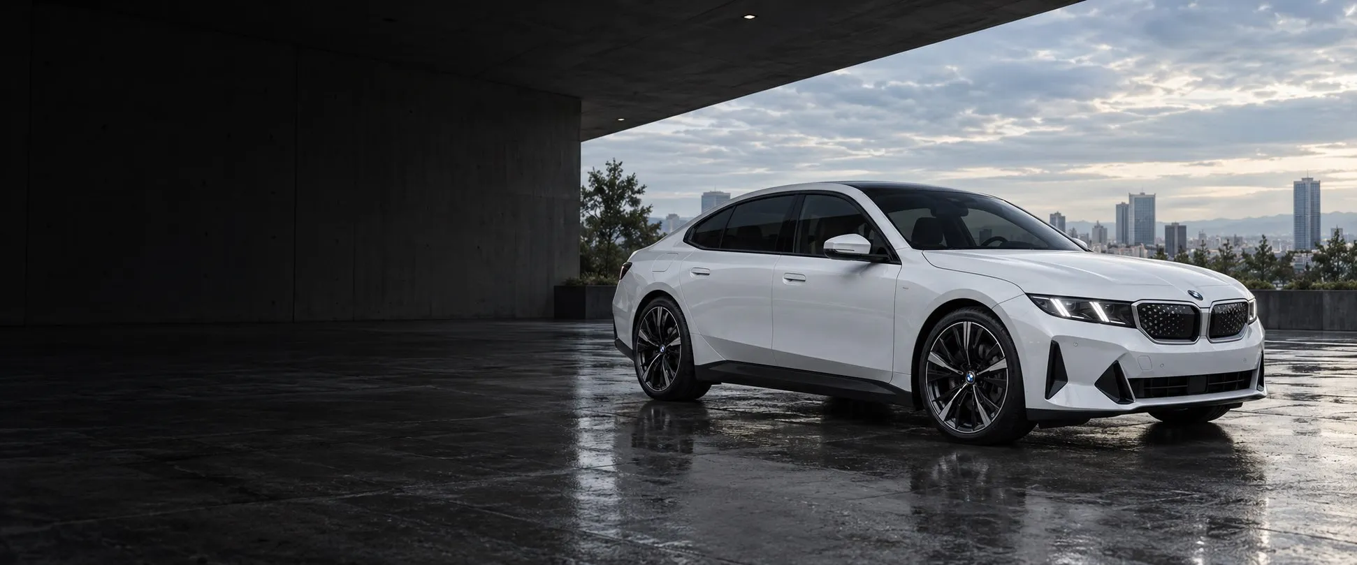 White BMW i3 sedan with dark tinted windows outside modern architecture
